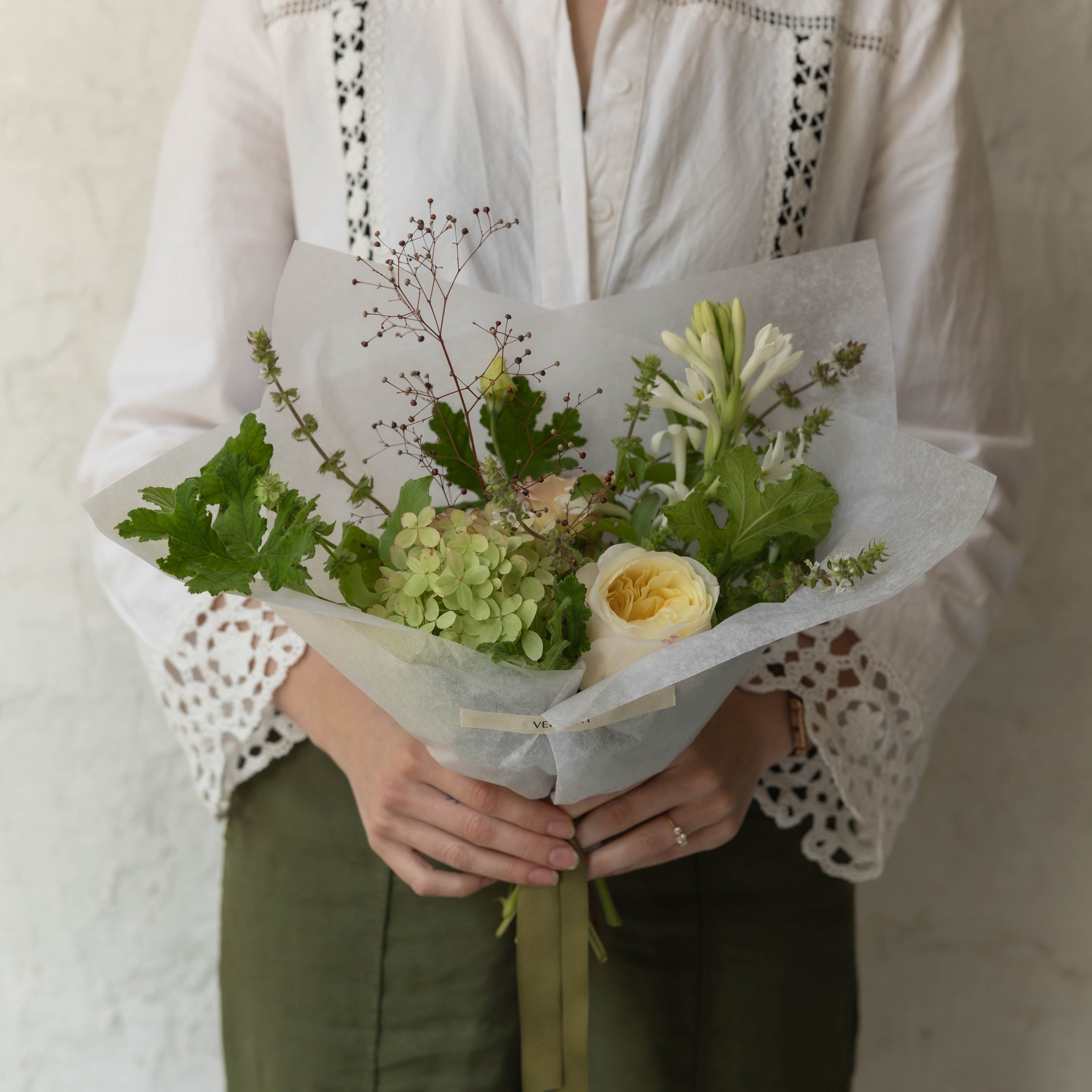 Person holding a bouquet of flowers against a plain background