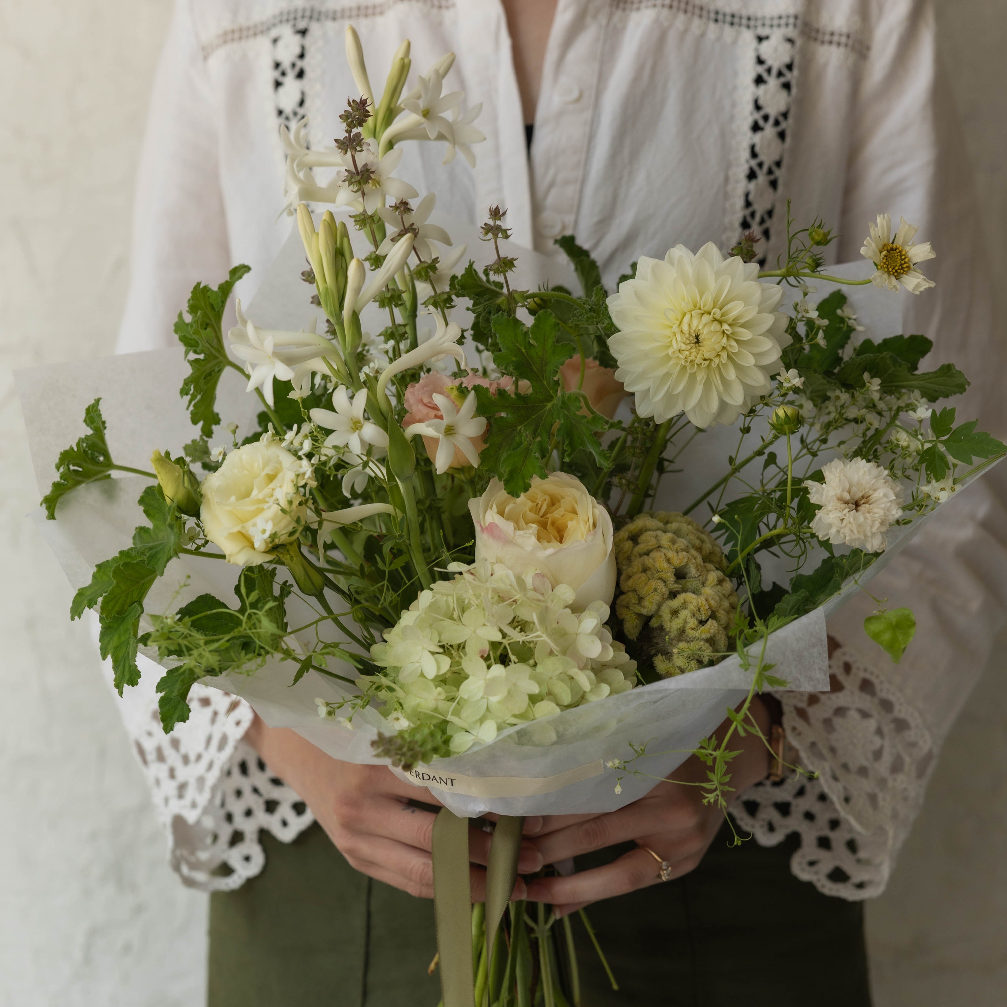 Person holding a bouquet of flowers against a light background